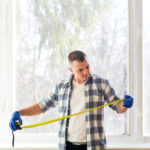 Mężczyzna mierzący otwór okienny przed montażem nowych okien