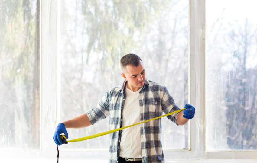Mężczyzna mierzący otwór okienny przed montażem nowych okien