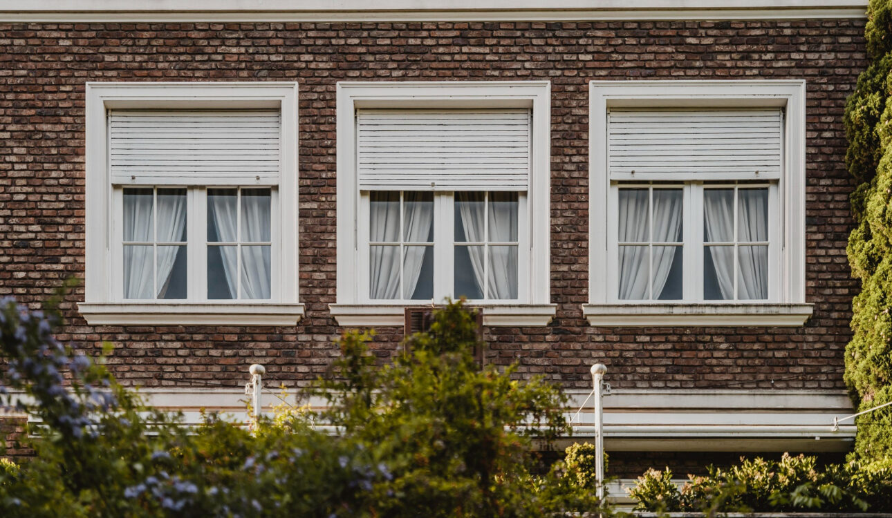 Trzy okna w istniejącym domu z opuszczonymi roletami zewnętrznymi